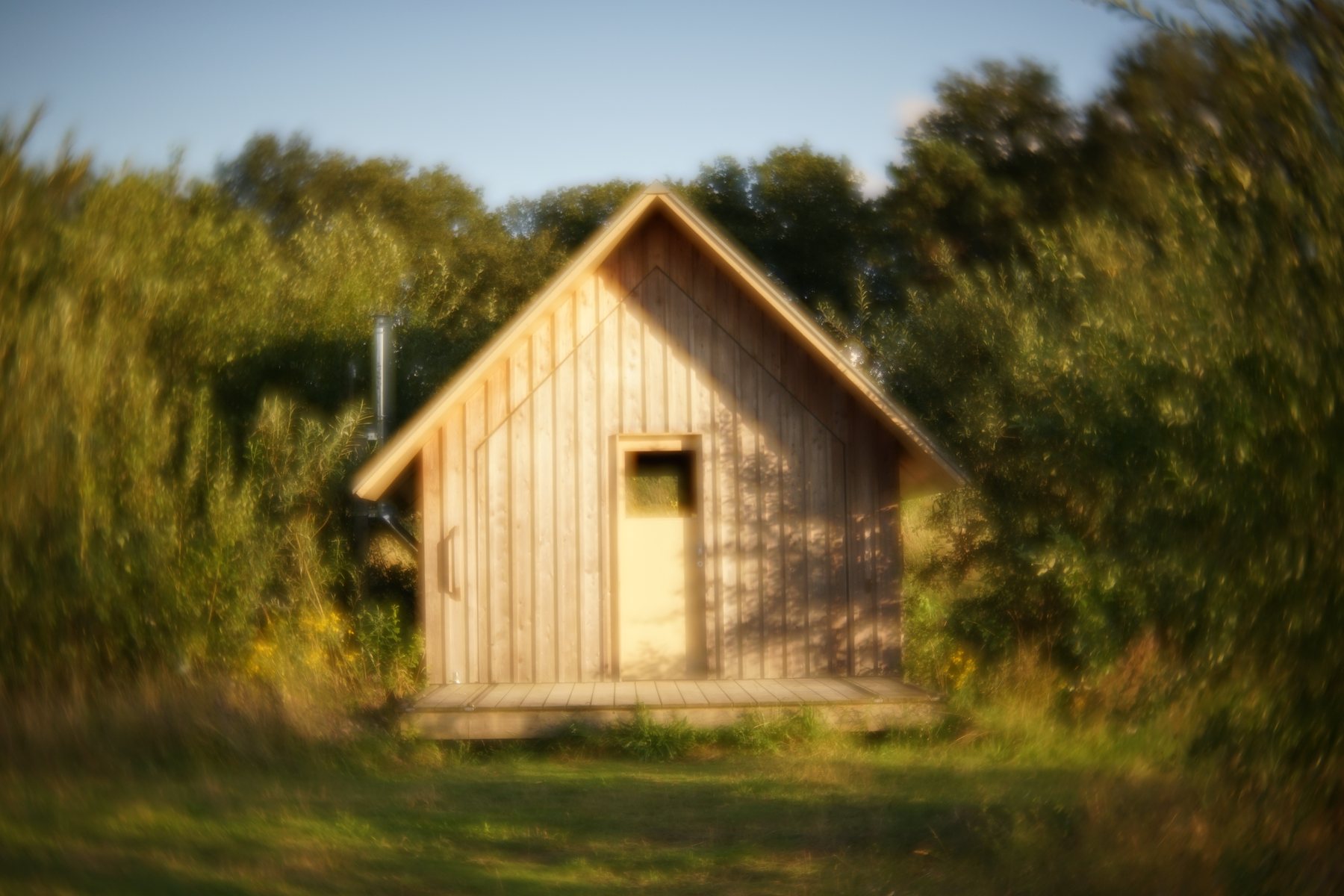 Een houten huisje in het groen, in het warme avondlicht